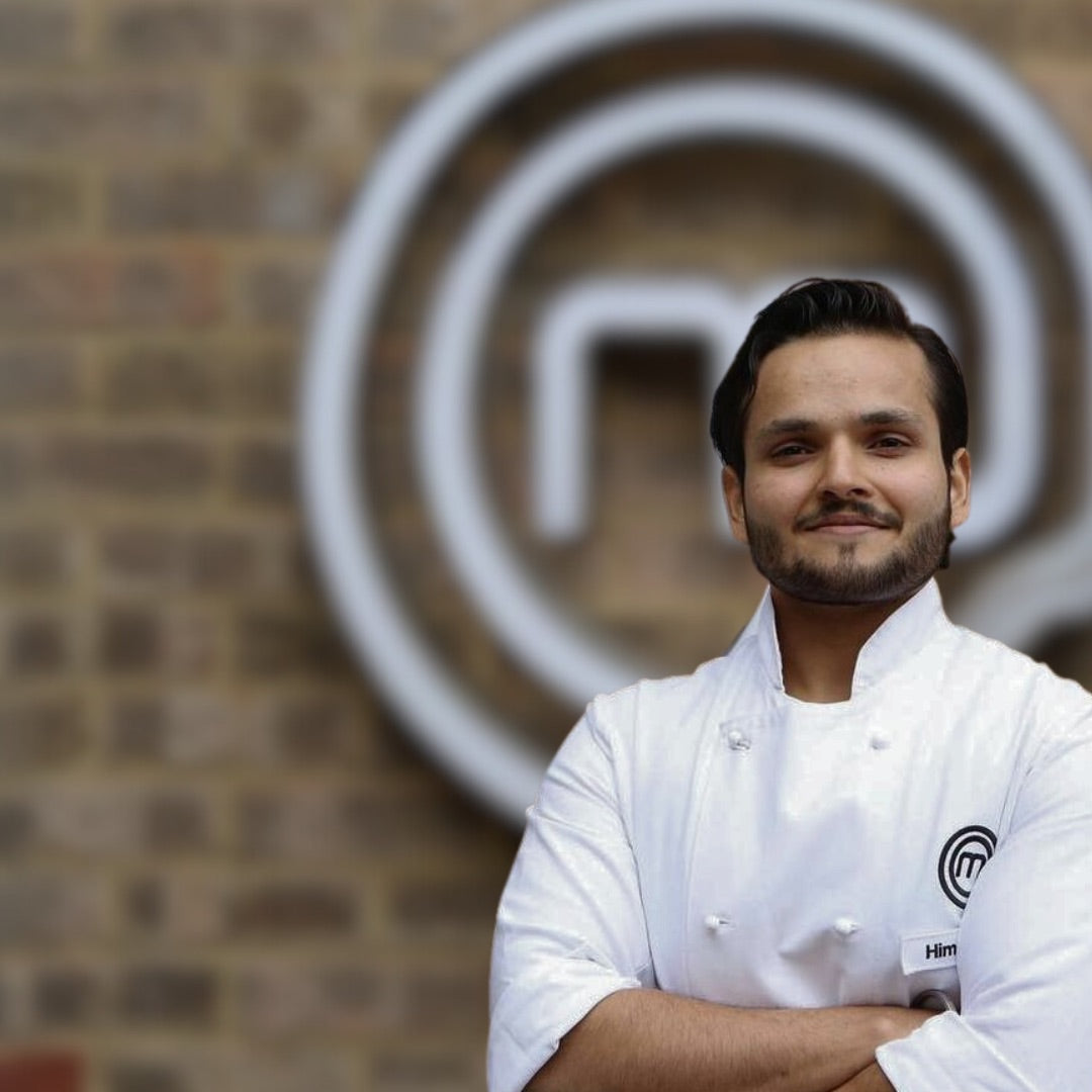 Person in a white chef jacket standing in front of a MasterChef logo